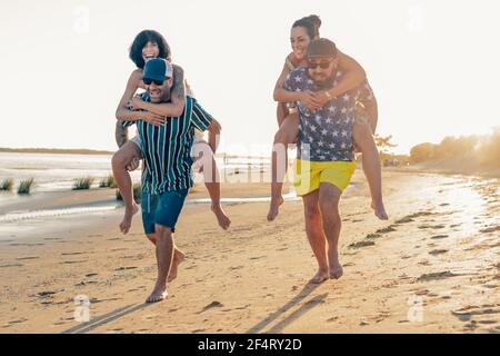 group of young friends on vacation having fun together on the beach. Group of friends doing a race on top of each other. Togetherness and leisure acti Stock Photo
