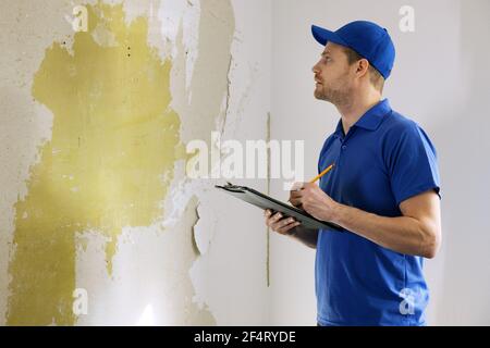 building contractor writing estimate on clipboard for house repair jobs. pricing calculation, renovation costs Stock Photo