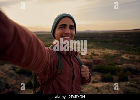 Young hiker on mountain during morning sunrise smiling and feeling fresh looking at camera Stock Photo