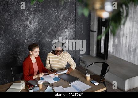 High angle portrait of two successful businesswomen discussing project at table in grey office, copy space Stock Photo