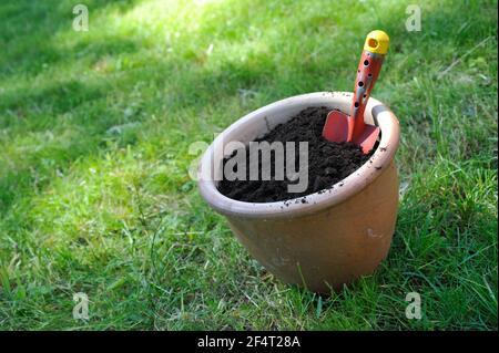 Flower pot filled with compost soil and garden shovel Stock Photo