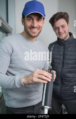 construction worker with colleague holding caulk gun Stock Photo