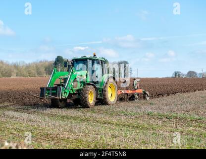 A farmer in a tractor ploughing a field in Yorkshire on a sunny spring day Stock Photo