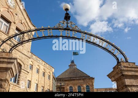 The ornate wrought iron John Smiths sign over the entrance to the John Smiths brewery in Tadcaster, North Yorkshire Stock Photo