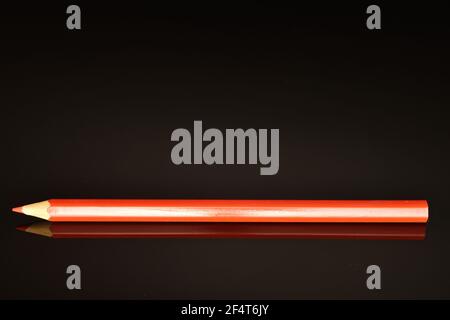 One red colored office pencil, close-up, on a black background. Stock Photo