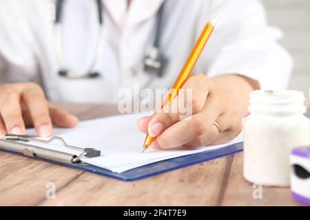 female doctor hand writing prescription on desk, close up. Stock Photo
