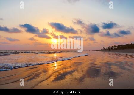 sunset landscape photo of Kuakata sea beach . evening sky reflected on wet sand . Stock Photo