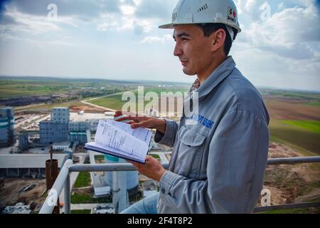 Standard Cement plant. Young Asian engineer with notebook on cement plant background. View from top. Stock Photo