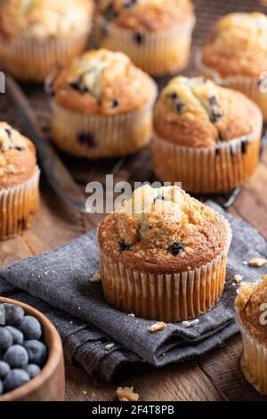 Blueberry muffin on a cloth napkin with muffins on a cooling rack in background Stock Photo