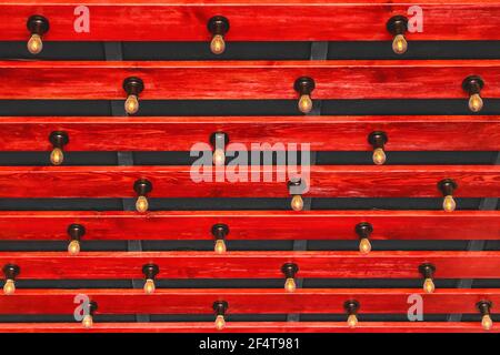 Modern wooden interior with red plank ceiling and light bulbs background. Stock Photo