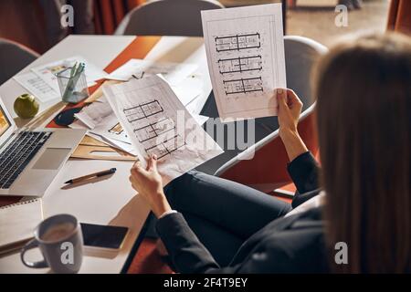 Draftswoman seated at the office desk analyzing the building plans Stock Photo