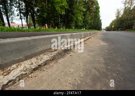 poorly executed road repairs. replacing the old curb stone with a new one Stock Photo
