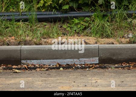 poorly executed road repairs. replacing the old curb stone with a new one Stock Photo
