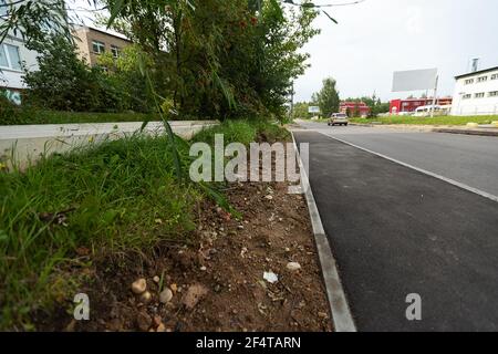 poorly executed road repairs. replacing the old curb stone with a new one Stock Photo