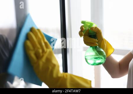 Housekeeper in gloves washing window with napkin closeup Stock Photo