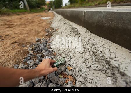 poorly executed road repairs. replacing the old curb stone with a new one Stock Photo