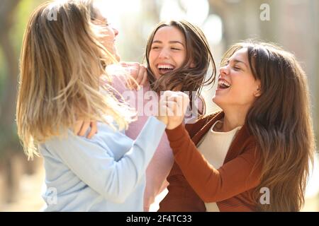 Three excited women friends jumping celebrating happiness in the street Stock Photo