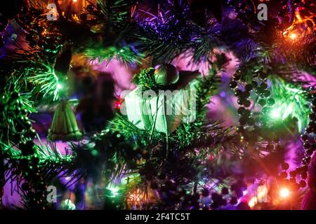 Decorative Christmas present on a Christmas tree in the dark surrounded by fairy lights and various other decorations. Stock Photo