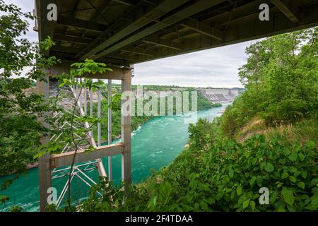 View beneath the Lewiston–Queenston Bridge showing the Niagara River flowing through a green gorge. Stock Photo