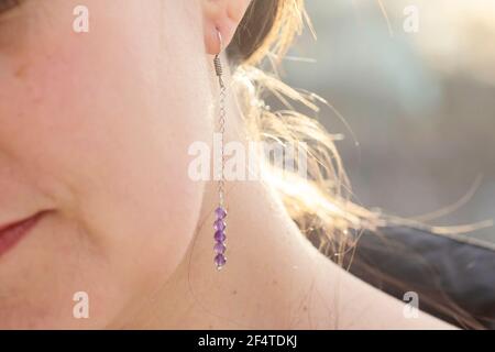 Female ear wearing long amethyst mineral stone earring Stock Photo