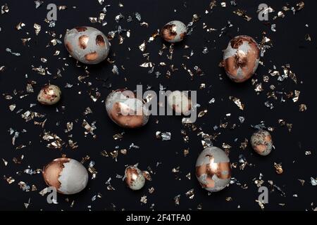Gilded eggs and shiny confetti on a black background. Stock Photo