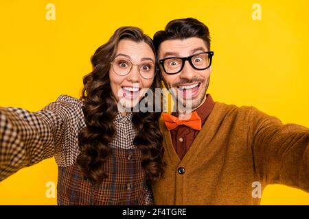 Self-portrait of attractive cheerful friends friendship couple embracing having fun isolated on bright yellow color background Stock Photo