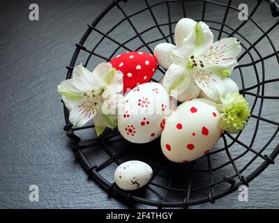 Easter eggs in a metal basket close up over a black stone background Stock Photo