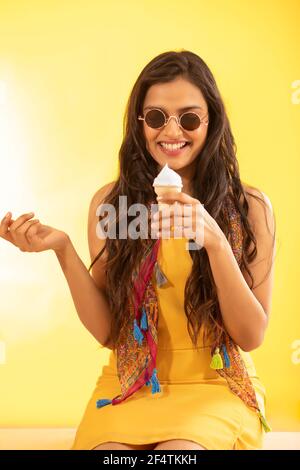 A WOMAN SITTING AND HAPPILY EATING ICE CREAM Stock Photo