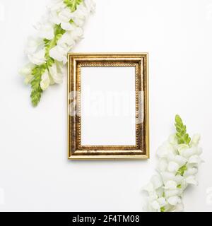 Empty photo frame with snapdragon flowers on white background. flat lay, top view, copy space Stock Photo
