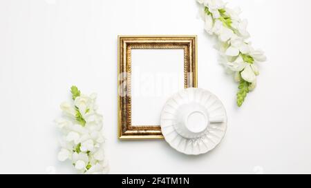 Empty photo frame with coffee cup, snapdragon flowers on white background. flat lay, top view, copy space Stock Photo
