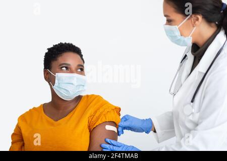 Doctor Sticking Plaster On Arm After Coronavirus Vaccination, White Background Stock Photo