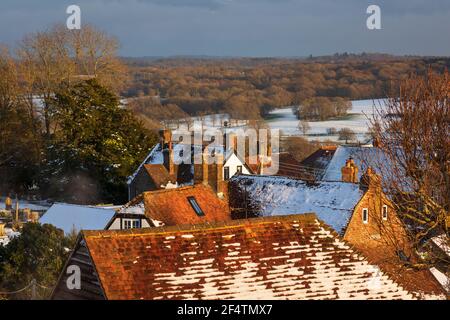 View over cottage rooftops and High Weald landscape in winter snow in late afternoon sunlight, Burwash, East Sussex, England, United Kingdom, Europe