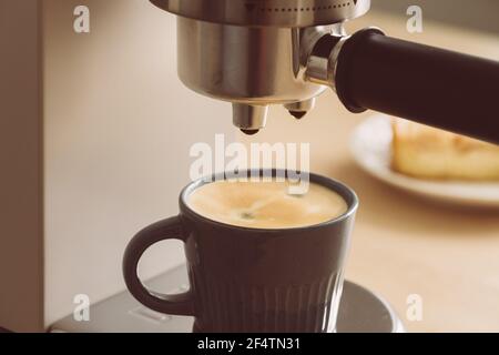 Morning ritual at breakfast with pouring coffee from coffee machine, making espresso Stock Photo
