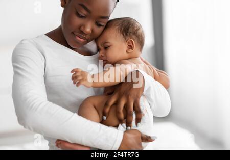 Black mother holding crying baby with colic on hands Stock Photo - Alamy