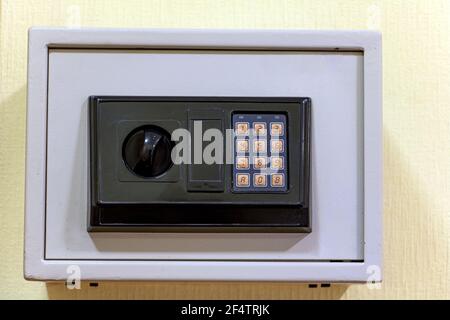 A small safe with a dial is mounted on the wall. Stock Photo