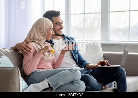 Young muslim family making purchases on Internet via laptop Stock Photo