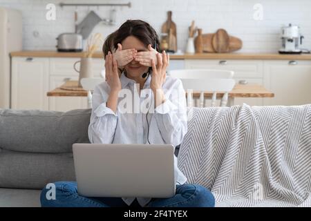 Mom work on laptop at home during lockdown, child distracts from work, covering her mother's eyes Stock Photo