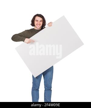 Contented young man holding a big blank banner for advertising pointing and showing with index finger. Happy guy with an empty sheet for text announce Stock Photo