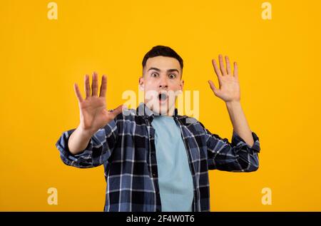 Scared Caucasian guy shouting in panic, making STOP gesture with both hands over orange studio background Stock Photo