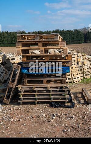 A stack of wooden pallets on top of each other with a pile of brick rubble behind with some bricks with holes Stock Photo