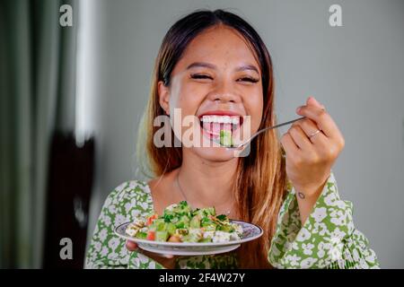 beautiful young asian woman eating healthy mediterranean food. smiling happy girl eating greek salad Stock Photo
