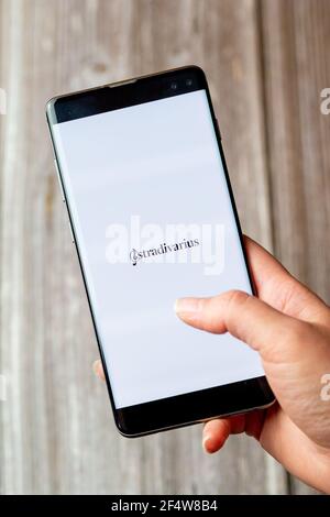 A mobile phone or cell phone being held in a hand with the Stradivarius app open on screen Stock Photo