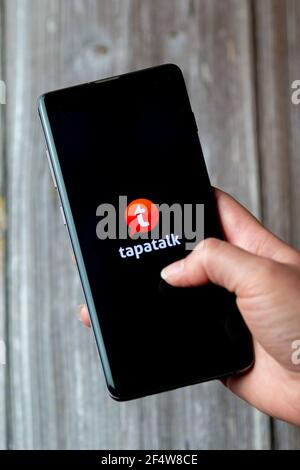 A mobile phone or cell phone being held in a hand with the Tapatalk app open on screen Stock Photo