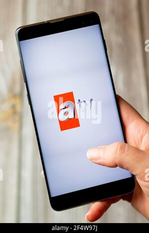 A mobile phone or cell phone being held in a hand with the ATV app open on screen Stock Photo