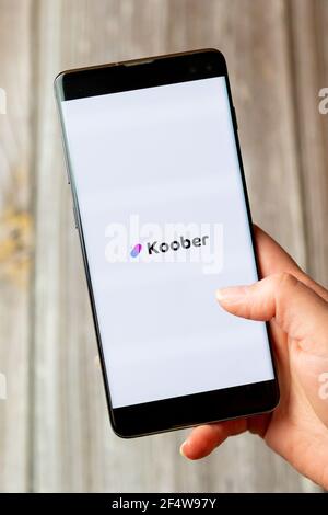 A mobile phone or cell phone being held in a hand with the Koober app open on screen Stock Photo