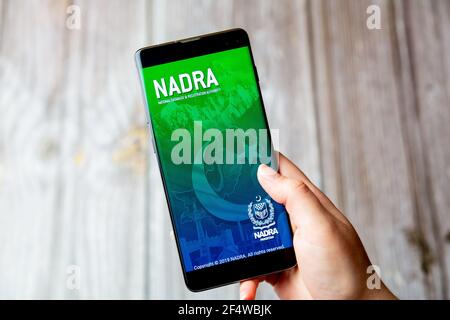 A mobile phone or cell phone being held in a hand with the NADRA app open on screen Stock Photo
