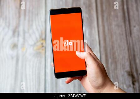 A mobile phone or cell phone being held in a hand with the Ria app open on screen Stock Photo