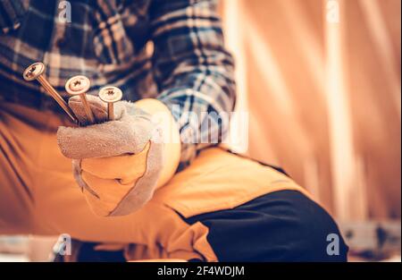 Construction Worker with Heavy Duty Wood Screw in His Hands Close Up. Wearing Industrial Safety Gloves. Stock Photo