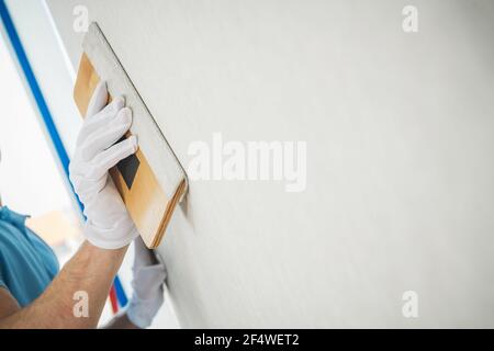 Vinyl Wallpapers Squeegee Tool in Use by Professional Caucasian Interior Renovation Worker. Stock Photo