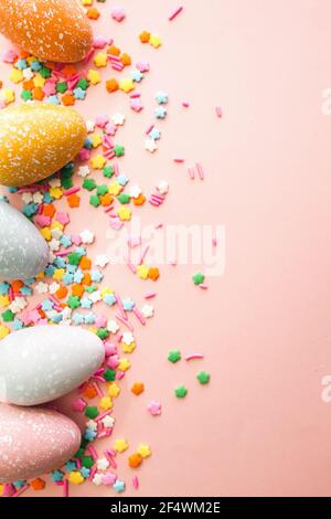 White, grey and yellow eggs on pink background with colourful sprinkles. Easter holiday background. Stock Photo